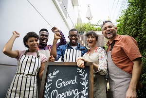 staff smiling at camera standing around grand opening sign